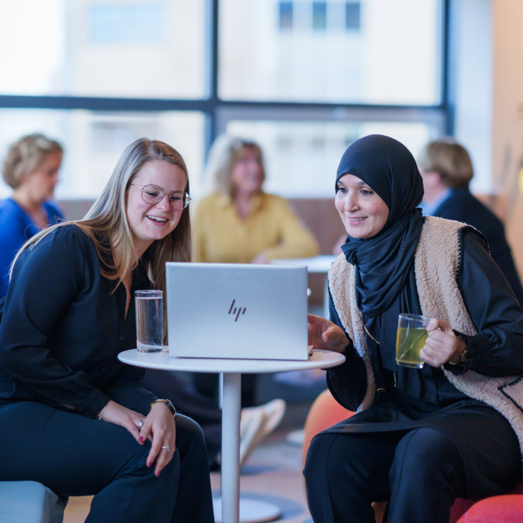 twee vrouwen zitten achter laptop